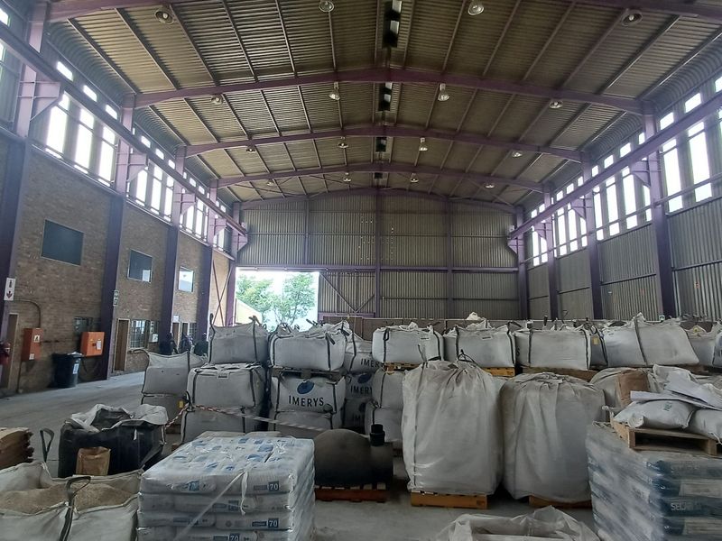 Spacious industrial warehouse featuring a high-clearance steel portal frame, corrugated metal walls, concrete flooring, and high-bay lighting, suitable for storage or manufacturing operations.