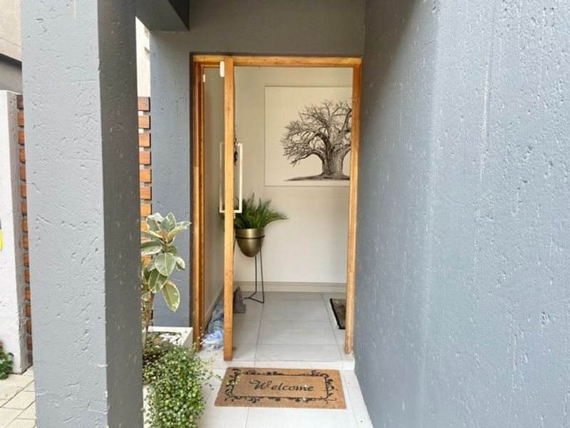 A modern, welcoming entrance featuring a natural timber door frame and clean tiled flooring, leading into a bright, minimalist interior space.