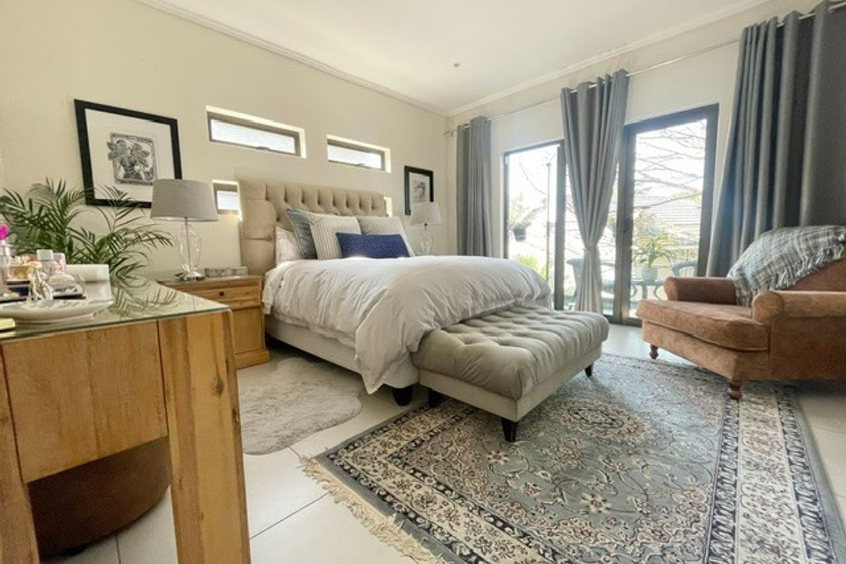 Spacious bedroom featuring tiled flooring, neutral walls, and large sliding glass doors providing natural light and access to the outdoor area.