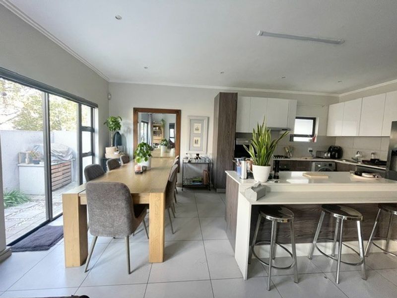 Modern open-plan living area featuring a contemporary kitchen with island, tiled flooring, and large sliding glass doors providing access to the outdoor space.