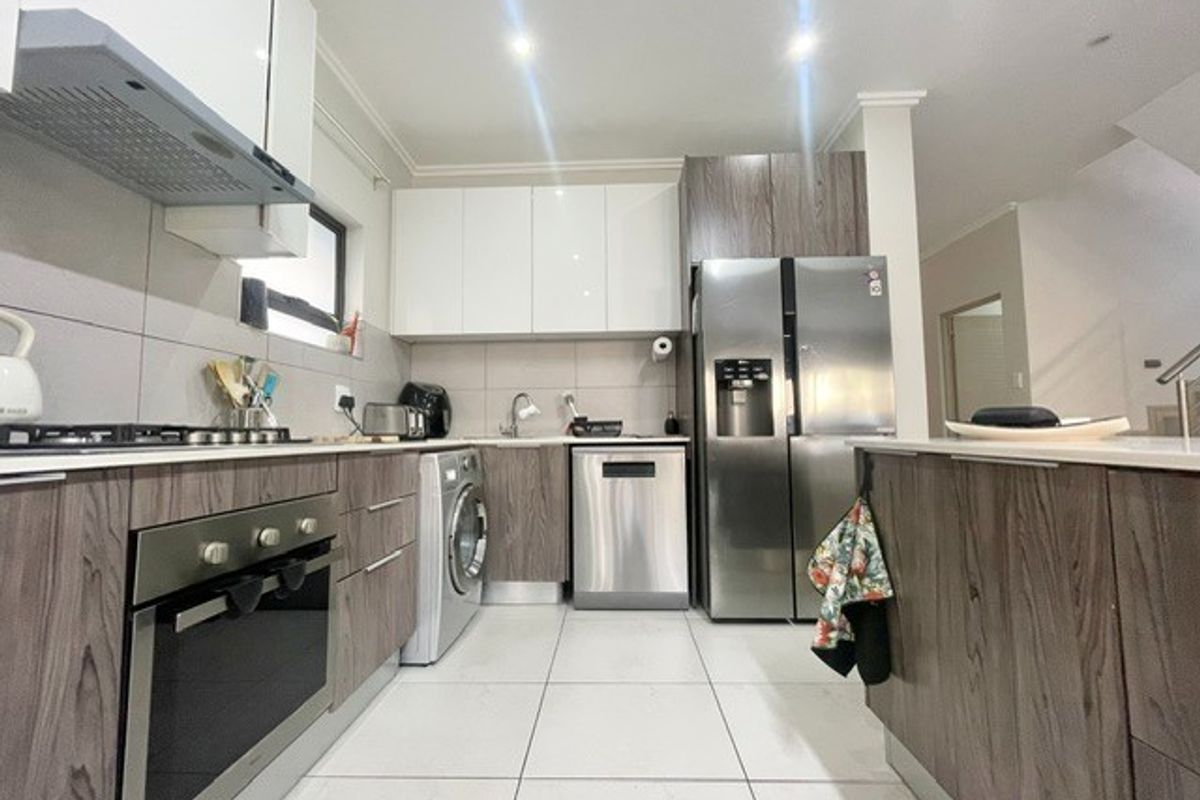 Modern kitchen featuring two-tone cabinetry, stainless steel appliances, gas hob, built-in oven, and tiled flooring with ample storage space.