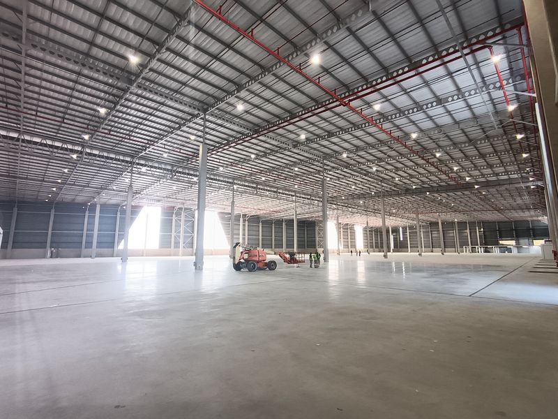 Expansive industrial warehouse space featuring high ceilings, polished concrete flooring, and integrated fire sprinkler systems, suitable for large-scale logistics or manufacturing operations.