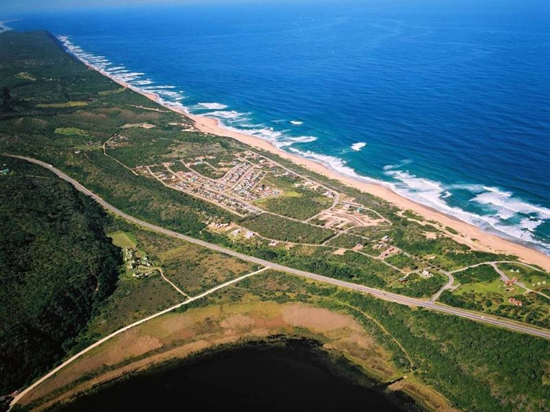 An expansive aerial view of the coastal residential area, showcasing the proximity to the ocean, natural lake, and surrounding landscape.