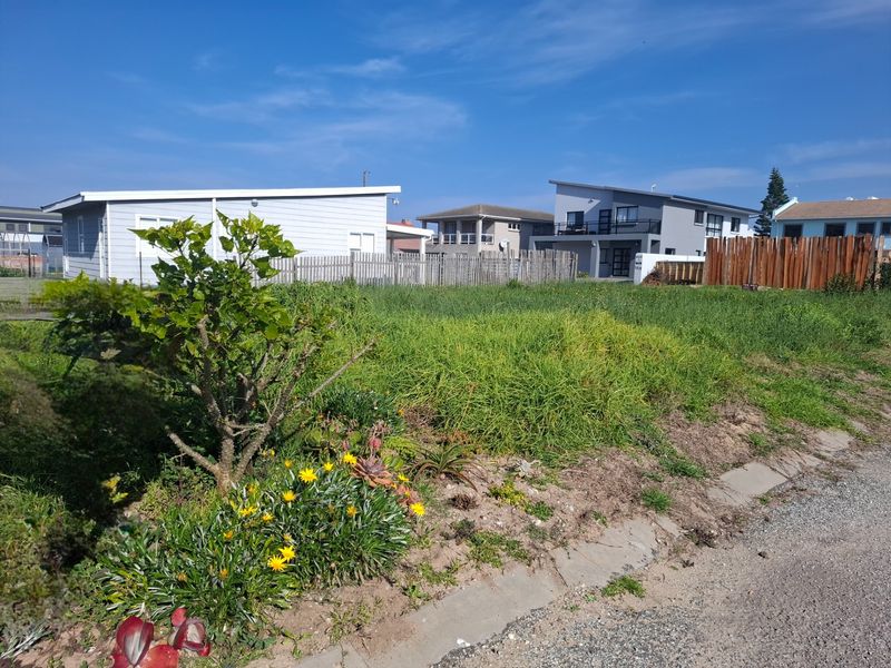A vacant residential plot featuring overgrown grass and established timber fencing, situated in a developed neighbourhood with paved street access.