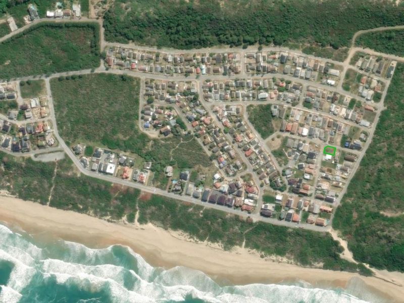 Aerial view of a coastal residential estate showing the property location highlighted in green within a developed neighborhood near the beach.