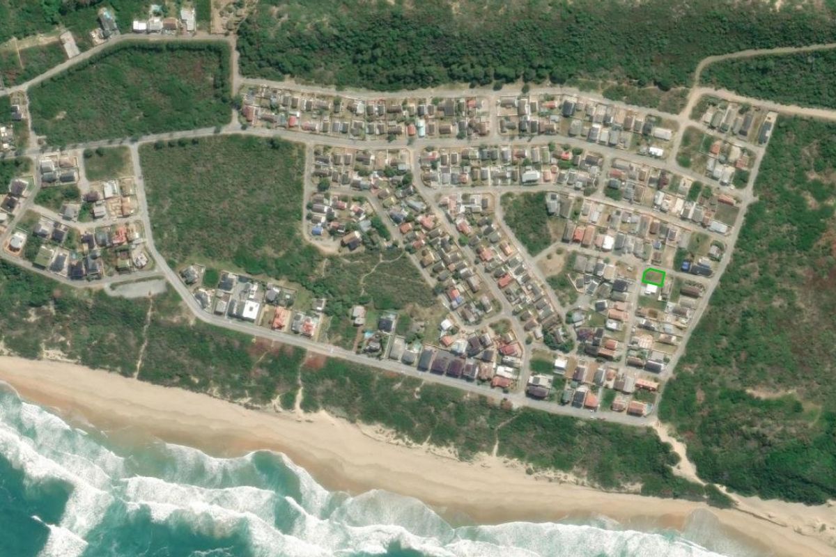 Aerial view of a coastal residential estate showing the property location highlighted in green within a developed neighborhood near the beach.
