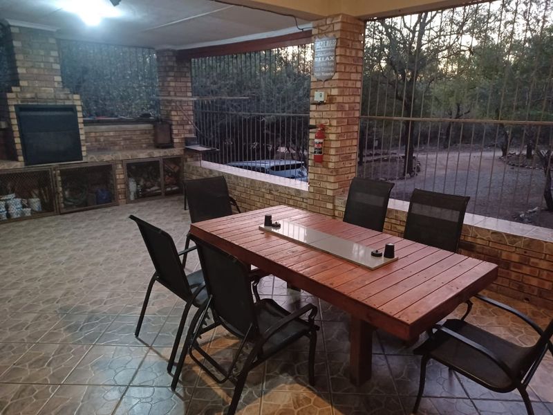 Covered outdoor patio featuring a built-in braai, brick pillars, and tiled flooring, providing a functional space for outdoor dining and entertainment.