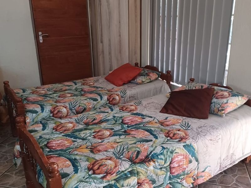 A bedroom featuring tiled flooring, a built-in wardrobe, and vertical blinds, showing signs of wear on the wall surfaces.