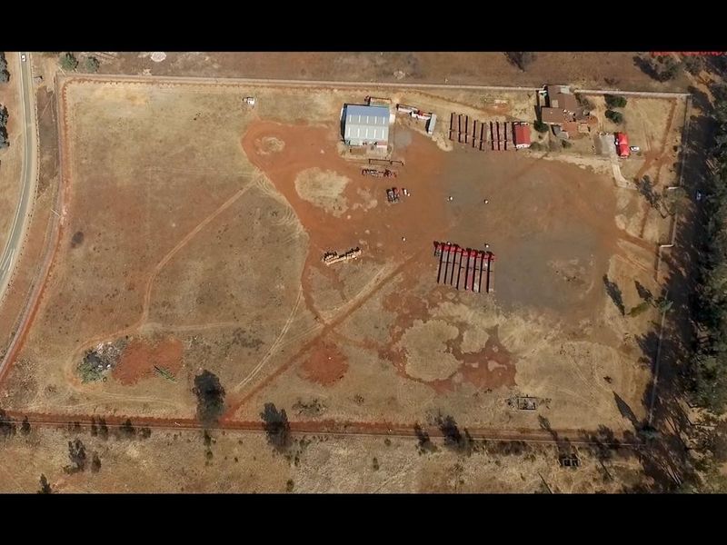 Aerial view of a large industrial property featuring a warehouse shed, extensive open yard space, and perimeter fencing.