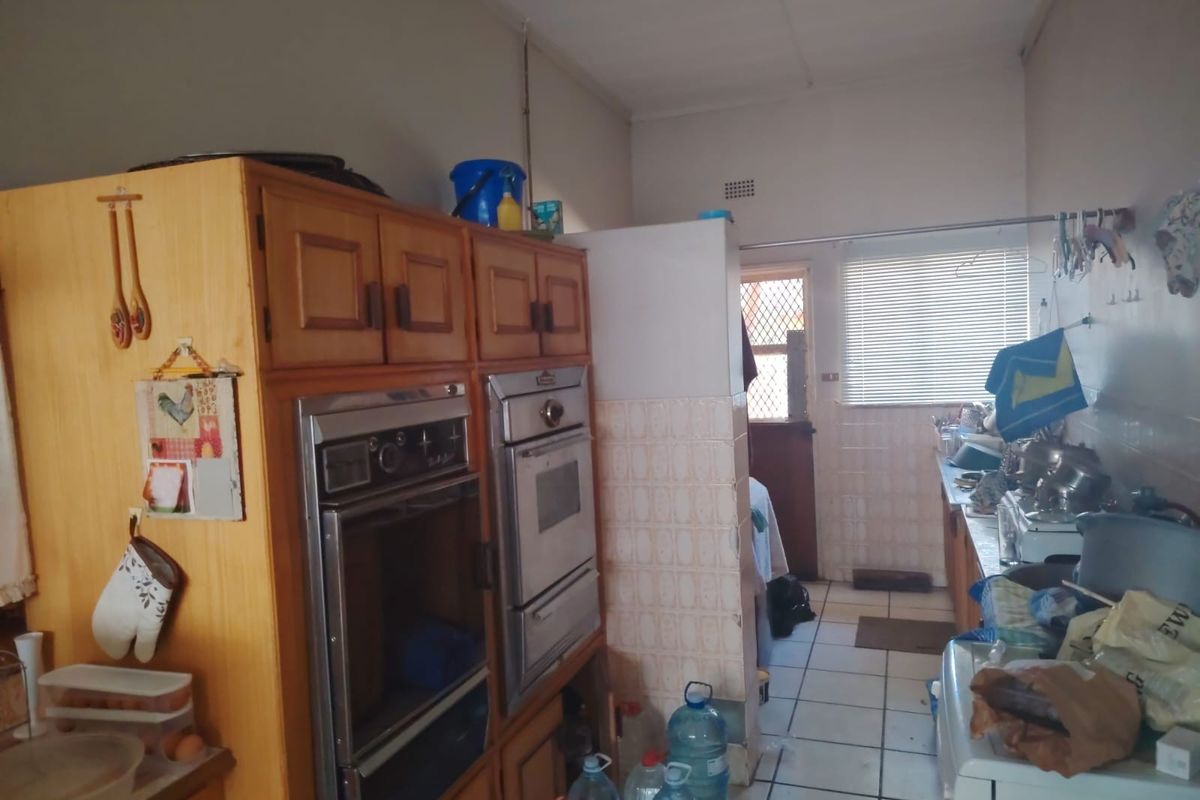 A dated kitchen featuring built-in wooden cabinetry, a double wall oven, and tiled flooring, offering potential for a modern renovation.