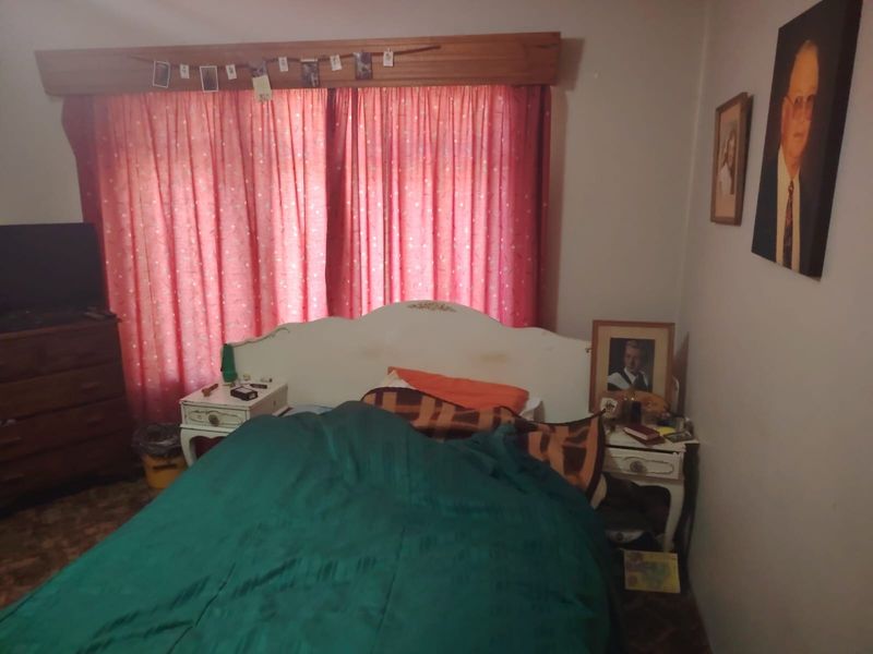 A bedroom featuring a wooden curtain pelmet and standard window treatments, requiring cosmetic updates to improve the overall aesthetic and appeal.