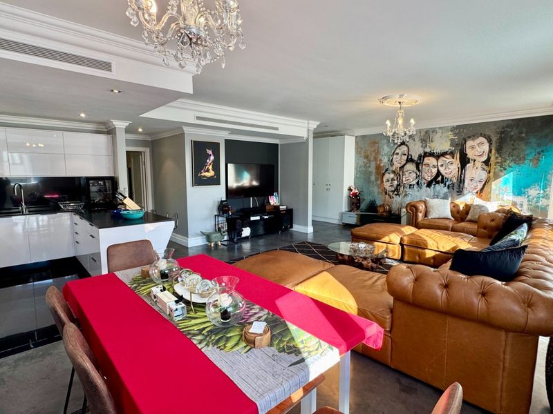 Spacious open-plan living area featuring a modern kitchen with high-gloss cabinetry, stone island, and integrated appliances, seamlessly flowing into the dining and lounge space.