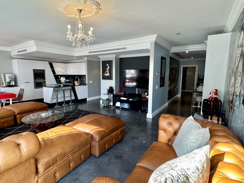 Spacious open-plan living area featuring a modern kitchen with built-in appliances, polished concrete floors, and elegant crown molding throughout the combined space.