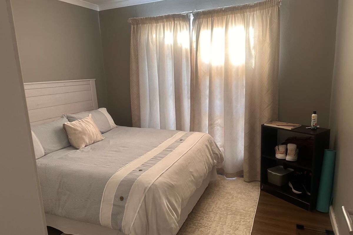 A functional bedroom featuring laminate flooring and neutral wall tones, providing a comfortable and well-lit sleeping space.