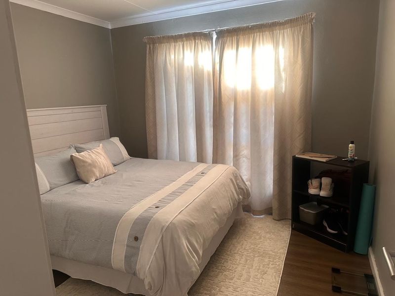 A functional bedroom featuring laminate flooring and neutral wall tones, providing a comfortable and well-lit sleeping space.