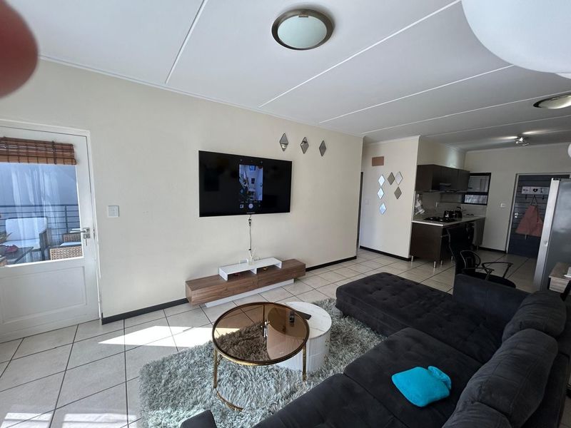 Open-plan living area featuring tiled floors, a modern kitchen with built-in cabinetry, and direct access to an outdoor patio space.