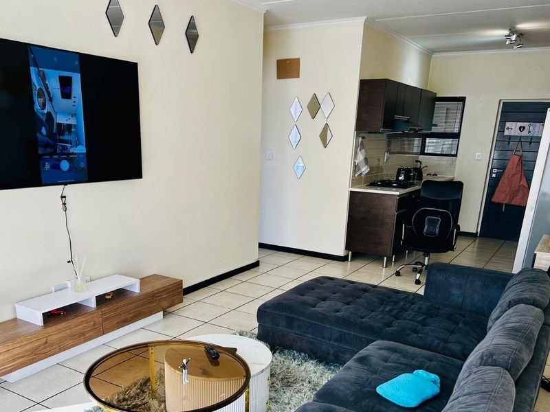 Open-plan living area featuring a compact kitchen with dark cabinetry, tiled flooring, and a seamless flow into the lounge space.