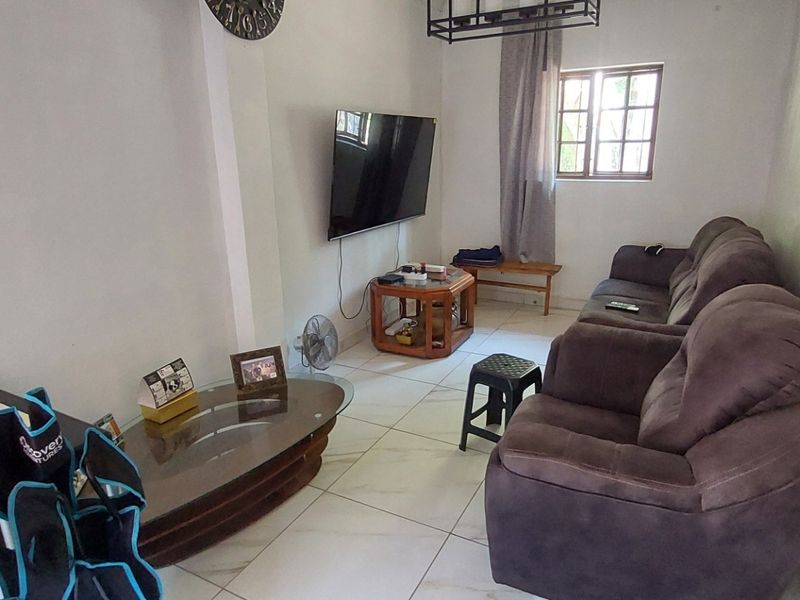 A functional living room featuring tiled flooring and a window, providing a neutral base for potential interior updates.