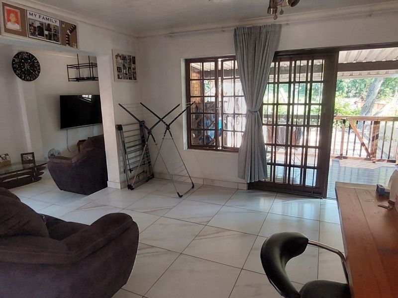 A living room featuring tiled flooring and a sliding glass door providing access to an outdoor patio area.