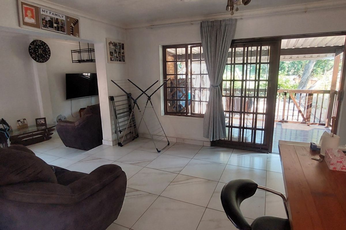 A living room featuring tiled flooring and a sliding glass door providing access to an outdoor patio area.