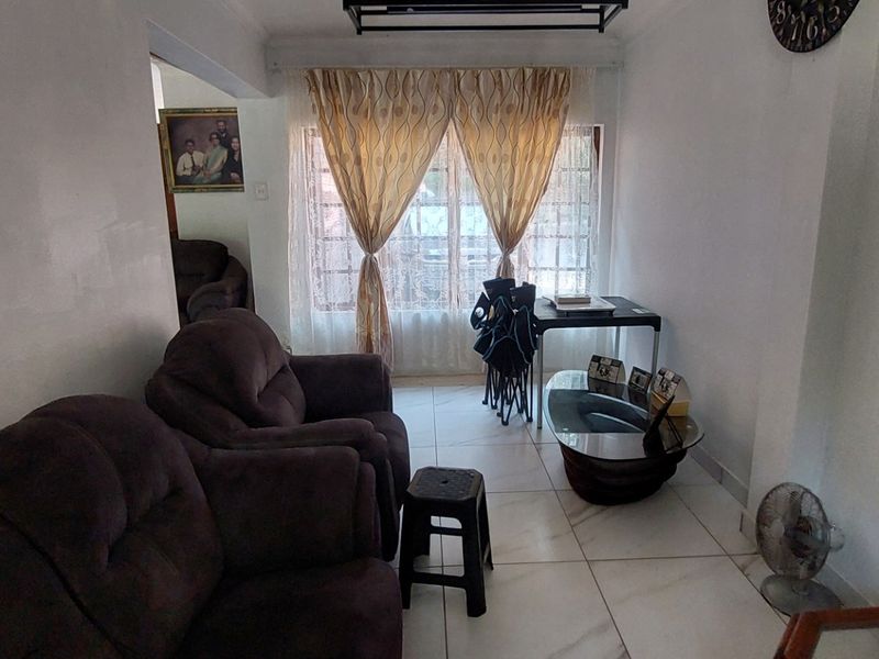 A living room featuring tiled flooring and a window with curtains, providing a functional space for relaxation.