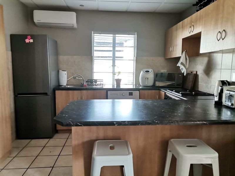 A functional kitchen featuring laminate cabinetry, dark countertops, a tiled backsplash, and an integrated air conditioning unit for climate control.