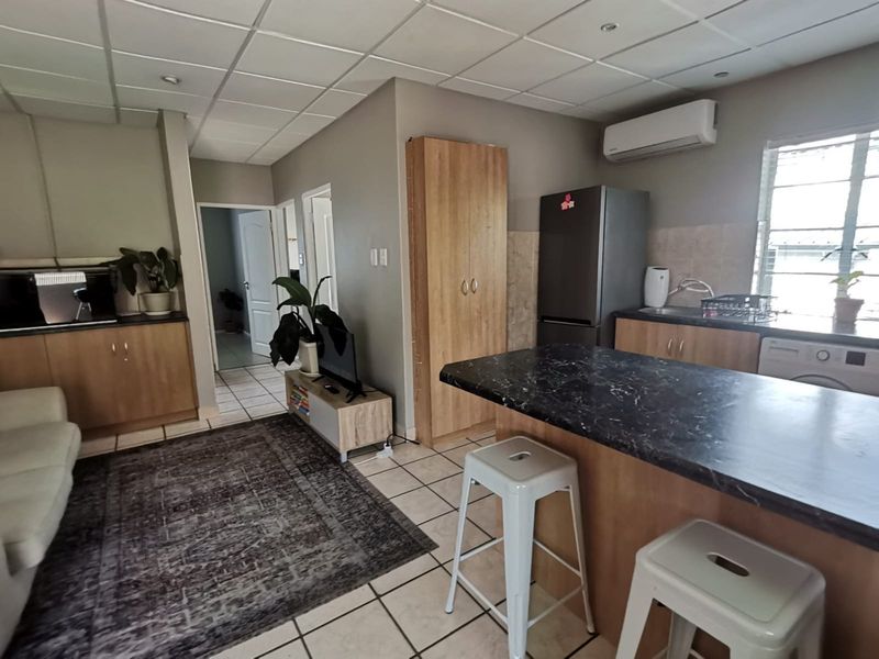 Open-plan living and kitchen area featuring tiled flooring, a kitchen island with laminate countertops, and a split-system air conditioner.