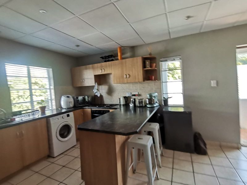 Functional kitchen featuring laminate cabinetry, dark countertops, built-in oven, hob, and tiled flooring, offering a practical layout with integrated laundry space.