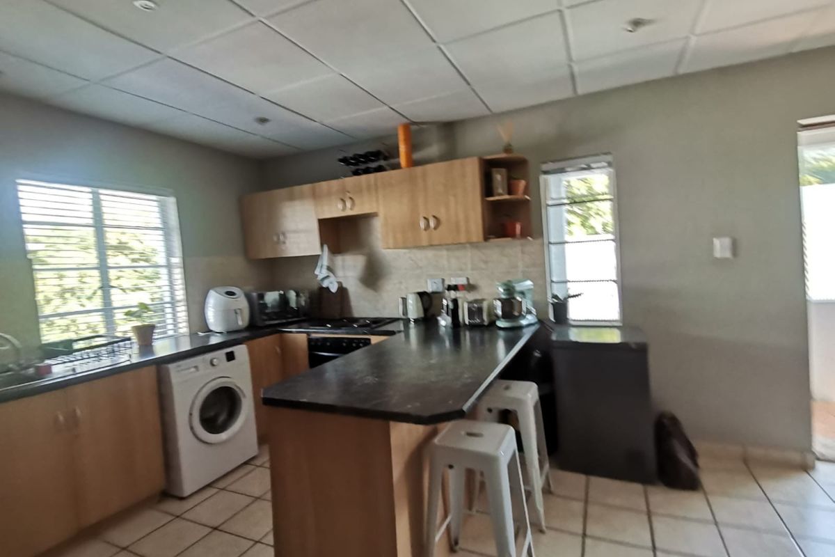 Functional kitchen featuring laminate cabinetry, dark countertops, built-in oven, hob, and tiled flooring, offering a practical layout with integrated laundry space.