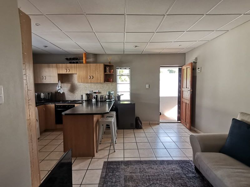 Open-plan living and kitchen area featuring tiled flooring, built-in cabinetry with laminate countertops, and direct access to an outdoor space.