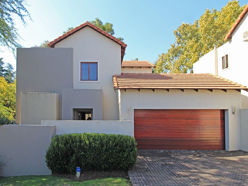 Front elevation of a modern house featuring a tiled roof, a wooden garage door, and a paved driveway.