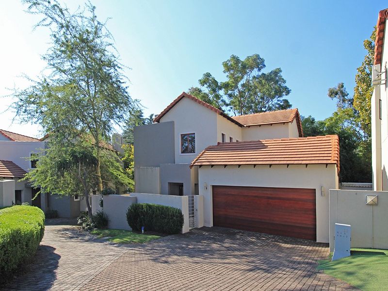 Front elevation of a modern residential house featuring a tiled roof, paved driveway, and a timber double garage door.
