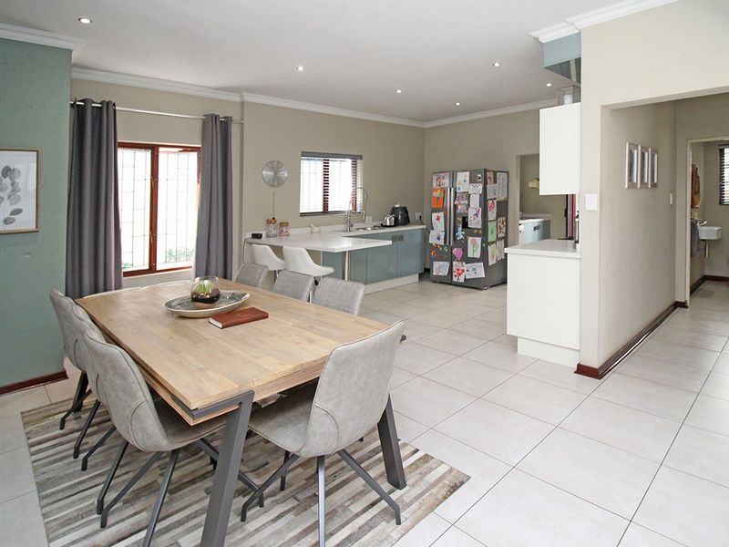 Spacious open-plan kitchen and dining area featuring tiled flooring, modern cabinetry, and a functional breakfast bar, seamlessly connecting to the living space.
