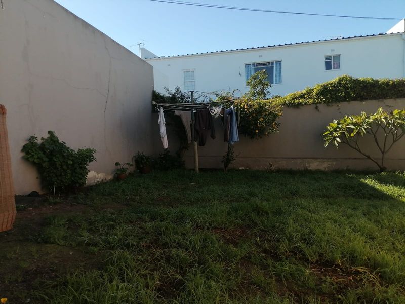 A private rear garden area featuring a lawn, established boundary walls, and a fixed washing line.