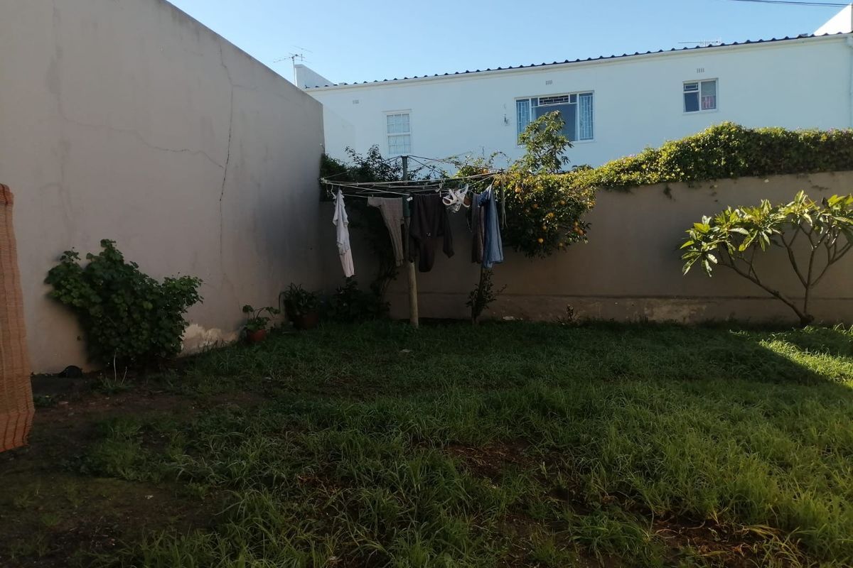A private rear garden area featuring a lawn, established boundary walls, and a fixed washing line.