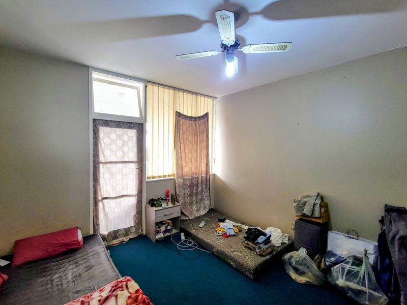 A bedroom featuring a ceiling fan, vertical blinds, and a glass panel door leading to an outdoor area.