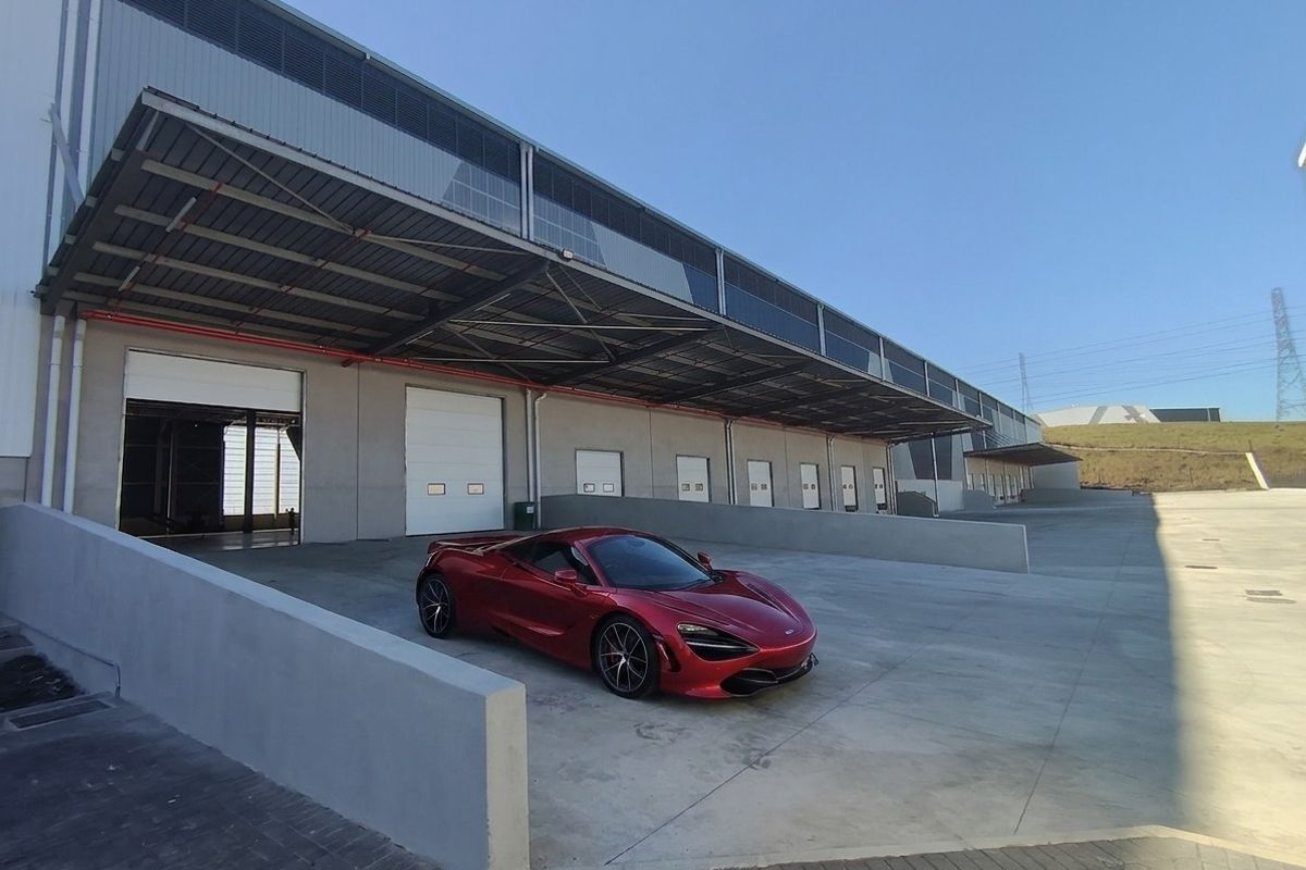 Industrial facility featuring multiple loading bays with roller shutter doors, a large concrete apron, and an extensive steel canopy for weather protection.