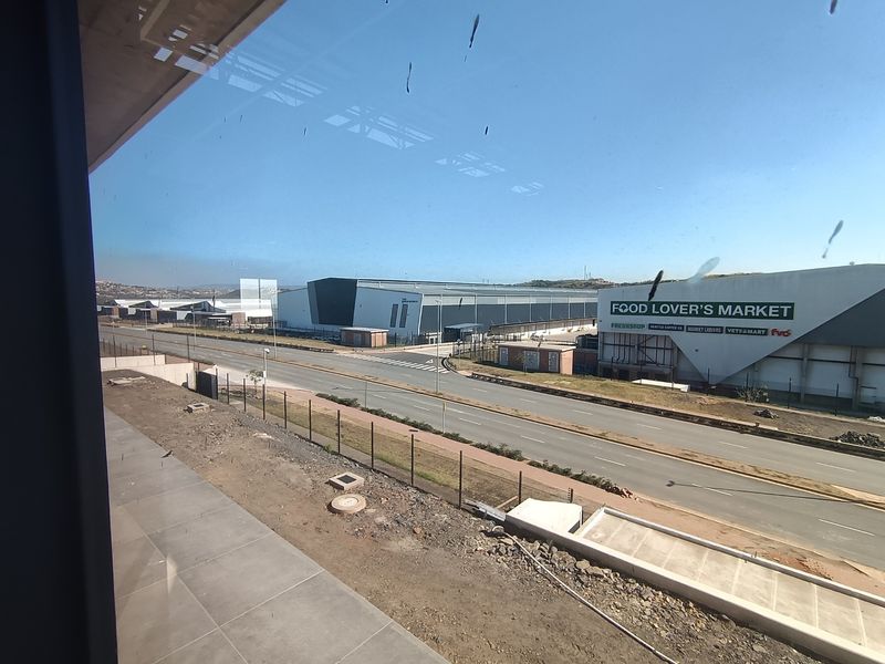 Elevated view overlooking an industrial park, featuring large warehouse facilities, a main access road, and perimeter security fencing.