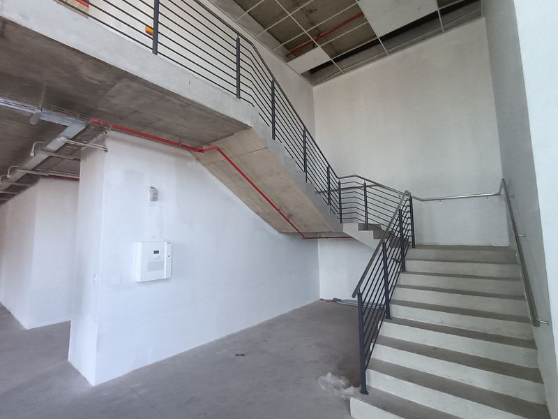 Industrial style interior space featuring a concrete staircase with metal railings and exposed ceiling infrastructure, suitable for commercial or creative office use.
