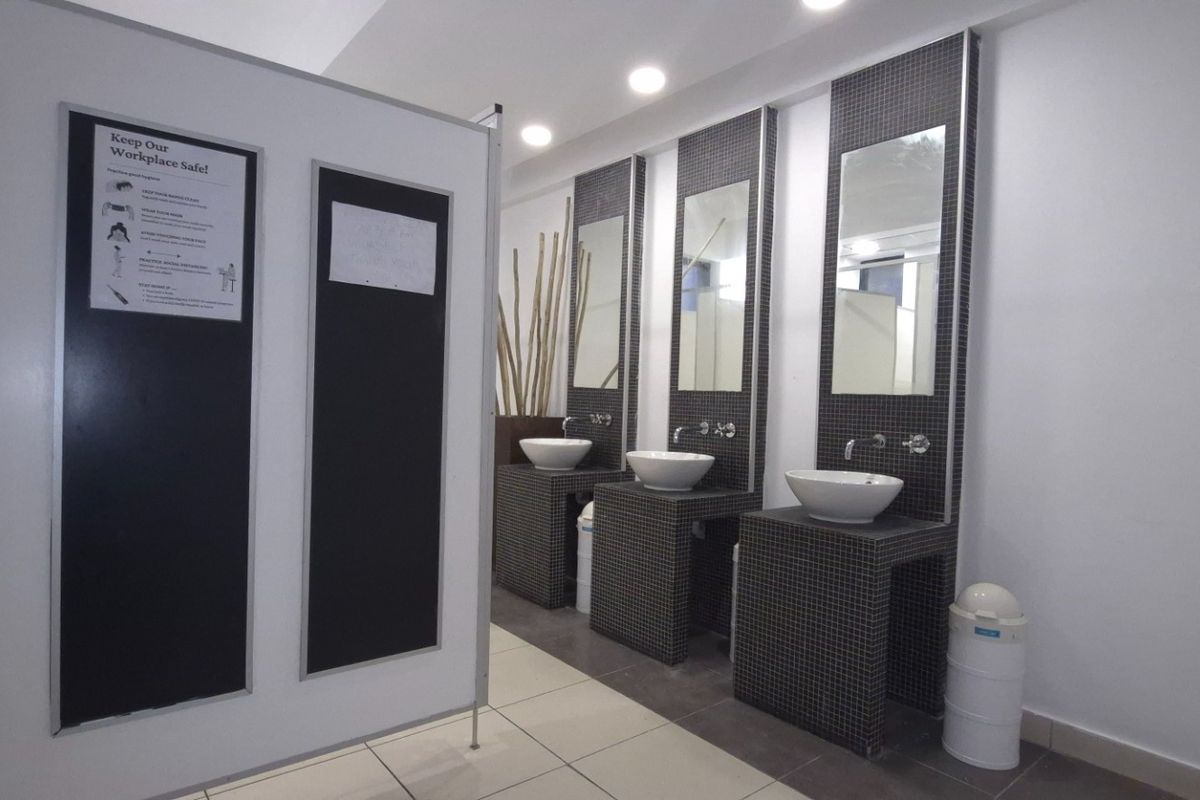 A commercial bathroom featuring three individual tiled vanity stations with vessel sinks, wall-mounted faucets, and integrated mirrors.