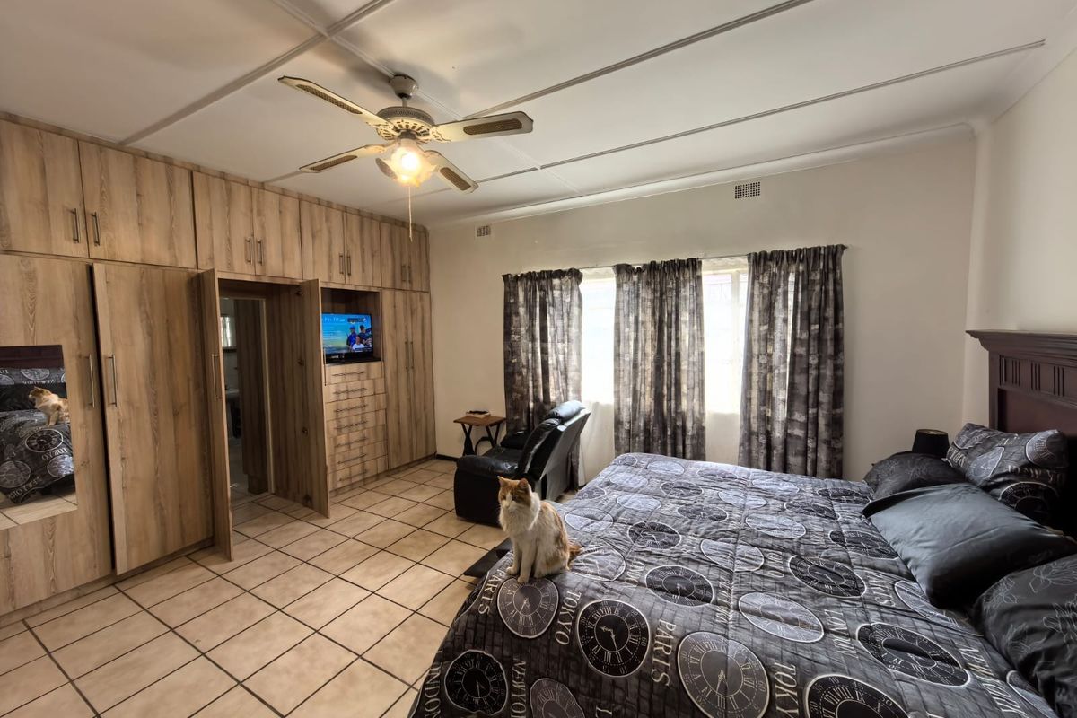 Spacious bedroom featuring extensive built-in wooden cabinetry, tiled flooring, and a ceiling fan, offering ample storage and functional living space.