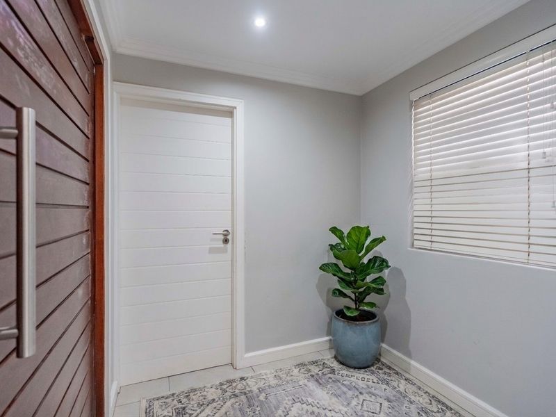 A bright and welcoming entrance hall featuring tiled flooring, recessed downlighting, and a solid timber front door with modern finishes.