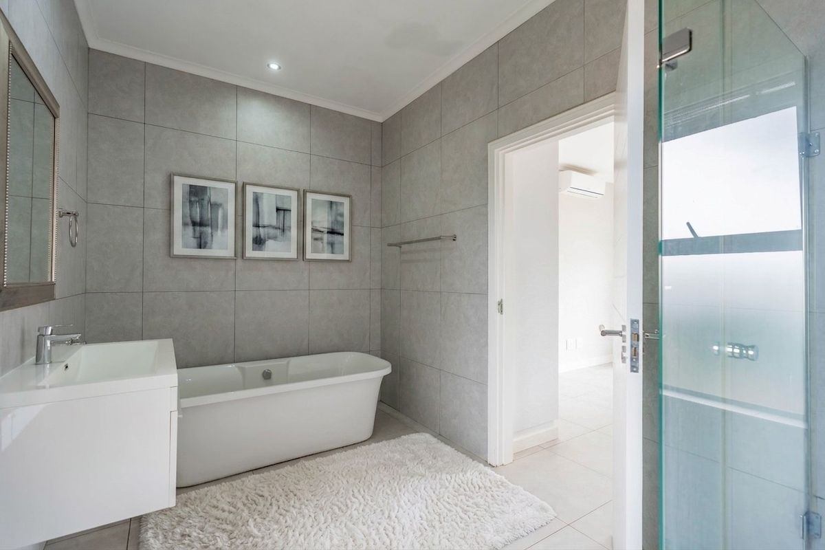 Modern bathroom featuring a sleek freestanding bathtub, contemporary vanity with basin, and floor-to-ceiling grey tiling, offering a clean and sophisticated aesthetic.