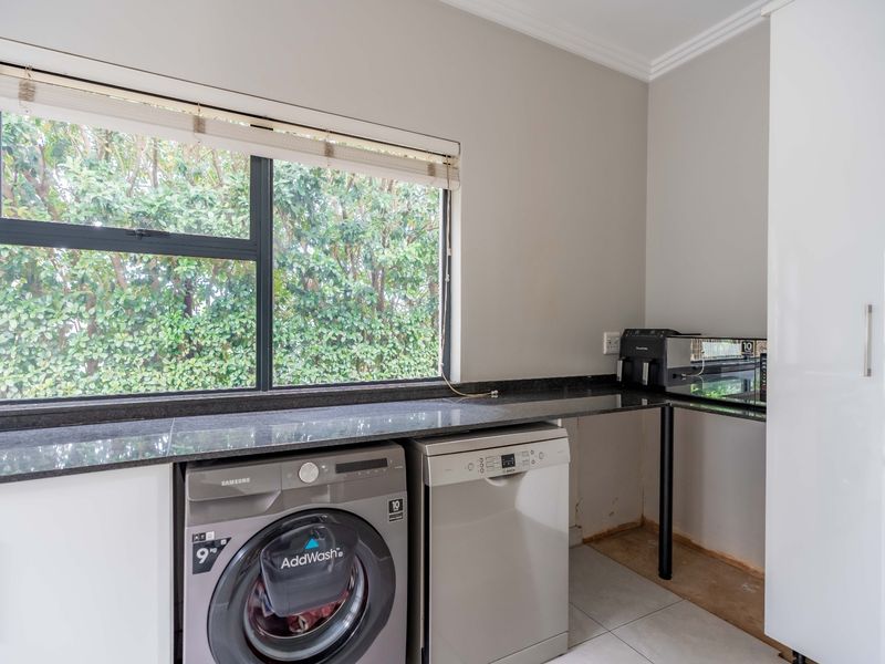 A functional laundry area featuring granite countertops, built-in cabinetry, and tiled flooring, with space for under-counter appliances.