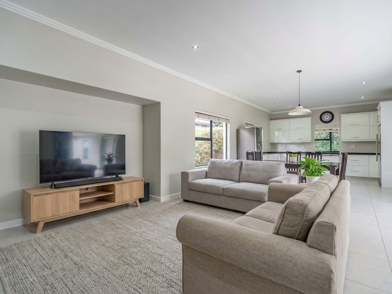 Spacious open-plan living area featuring a modern kitchen with sleek cabinetry and tiled flooring, seamlessly flowing into a comfortable lounge space.