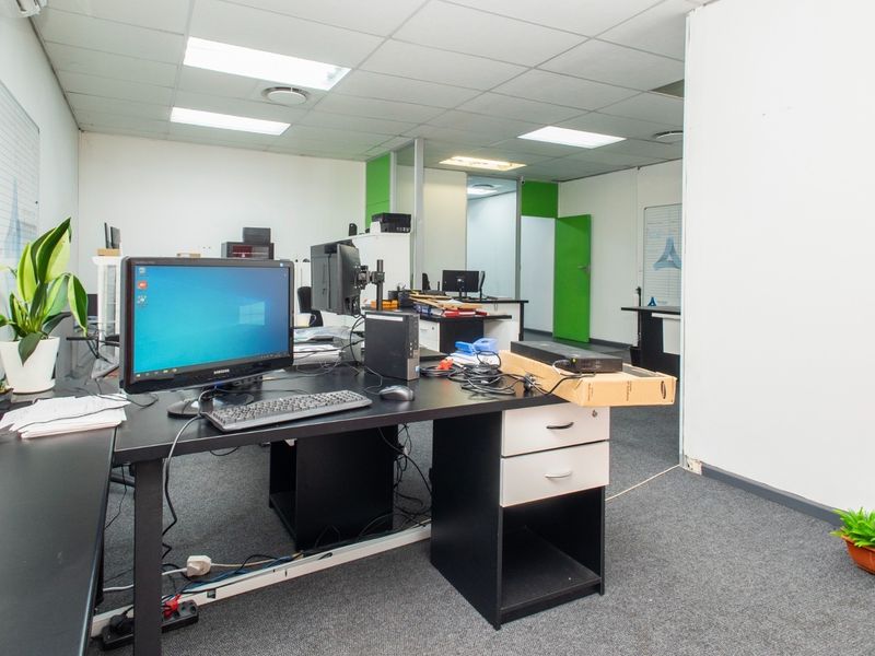 A functional office space featuring a suspended ceiling, recessed lighting, and carpeted flooring, providing a practical work environment.