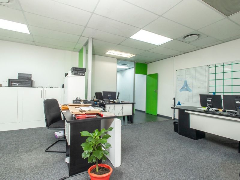 A functional office space featuring carpeted flooring, a suspended ceiling with recessed lighting, and built-in storage cabinetry.