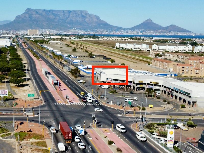 Aerial view of a commercial office complex situated along a major road, featuring ample parking and prominent street-level visibility.
