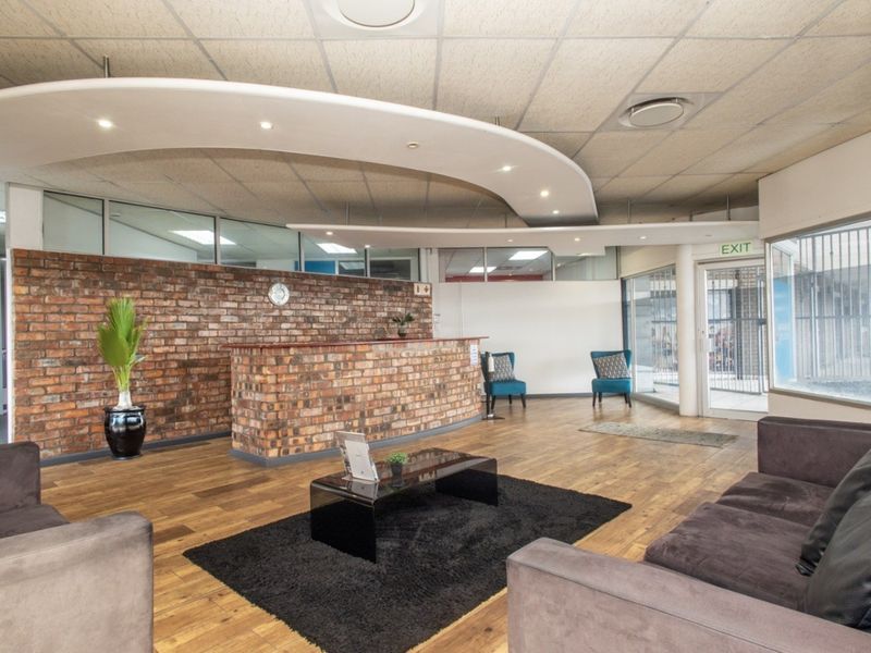 A professional office reception area featuring an exposed brick wall, built-in reception desk, and modern suspended bulkhead ceiling with integrated lighting.