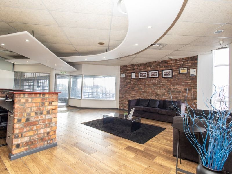Professional office reception area featuring exposed brick accents, wood-look flooring, and a modern suspended ceiling design with integrated lighting.
